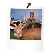 a hunter holding a dead deer with large antlers