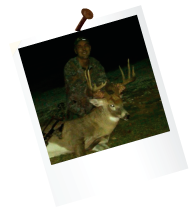 hunter holding antlers of dead deer with a bow and arrow by them