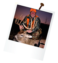 hunter with orange hat out at dawn holding antlers of large deer
