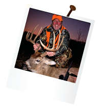 hunter with orange hat out at dawn holding antlers of large deer