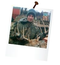 hunter on a farm holding the rack of a dead deer in the back of a pickup