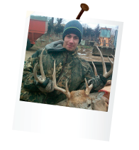hunter on a farm holding the rack of a dead deer in the back of a pickup